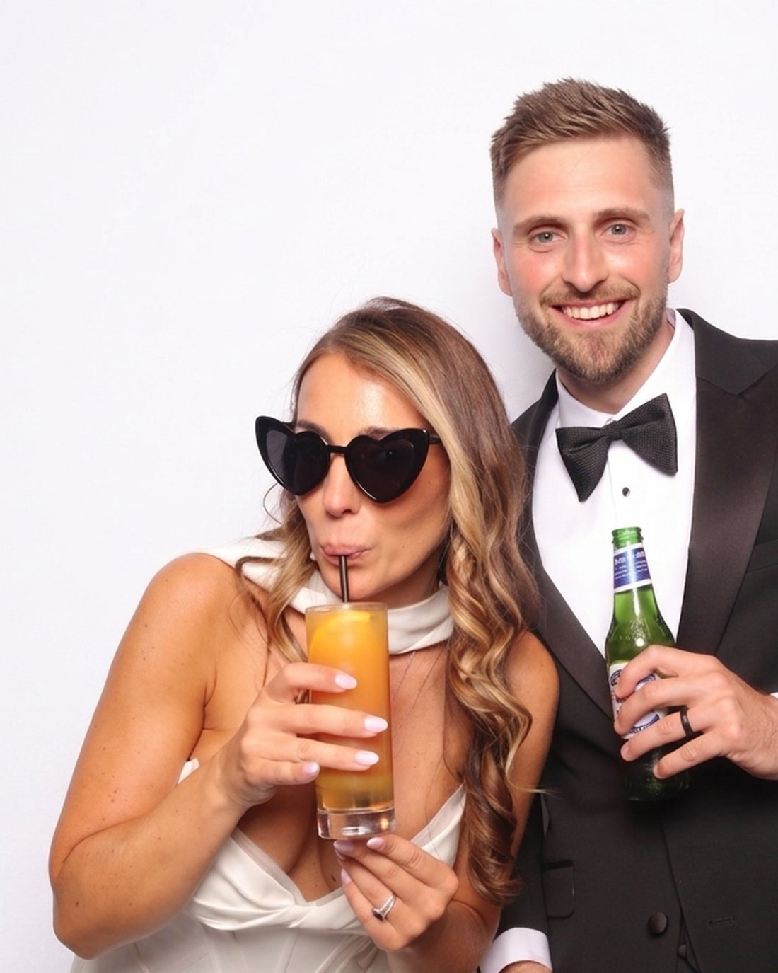 A bride and groom posing with props in the IkonikShots photobooth